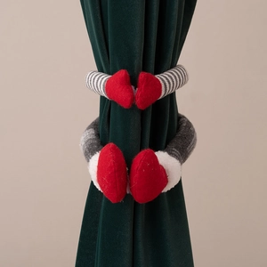 Détail de boucles de rideau gnome de Noël avec mains de cœur rouge sur velours