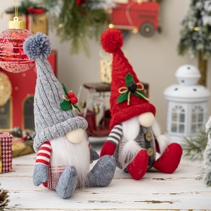 Set of two Nordic sitting Christmas gnomes with knitted hats on white wooden surface