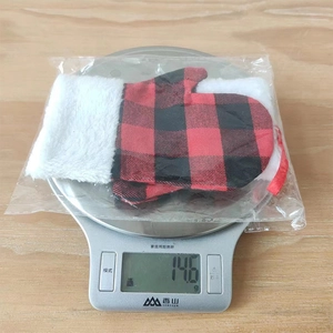 Peso di 14.6g per il guanto natalizio decorativo a quadri rossi e neri mostrato sulla bilancia