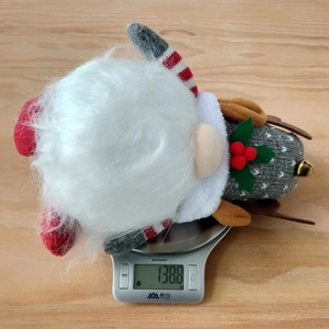 Détail d'un gnome de Noël en peluche sur une balance indiquant un poids de 138,8 g
