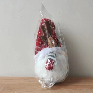 Détail d'un gnome de Noël avec chapeau à pois rouges et bois dans un emballage clair