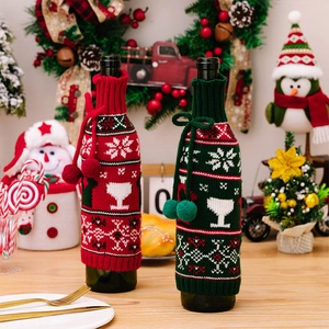 Close-up of Christmas knit wine bottle cover with snowflake patterns and pompom drawstrings