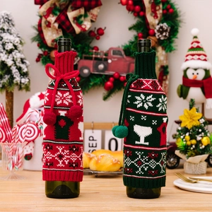 Close-up of festive knitted Christmas wine bottle covers with snowflakes and pom-poms