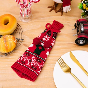 Detail of red Christmas knitted wine bottle cover with bow and festive snowflake patterns