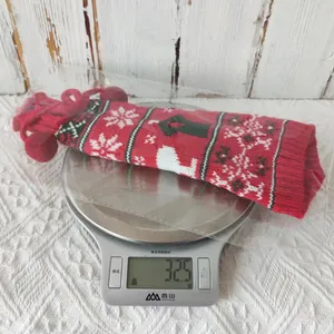 Close-up of red knitted Christmas wine bottle cover with snowflake patterns and pom pom