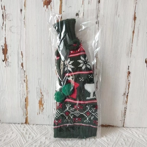 Close-up of knitted Christmas wine bottle cover with reindeer and snowflake patterns