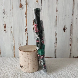 Detail of Christmas knitted wine bottle cover with green snowflake patterns in packaging