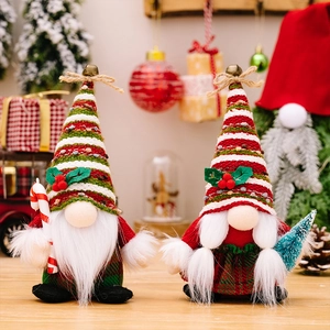 Detail of Christmas gnomes with knitted caps holding candy cane and pine tree decor