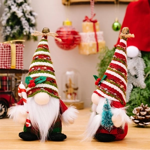 Close-up of plush Christmas gnomes with striped hats holding candy cane and tree