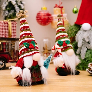 Detail of plush Christmas gnomes with striped hats holding a mini tree and candy cane