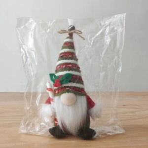 Detail of Christmas gnome plush with striped knit hat and candy cane in clear packaging