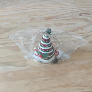 Detail of knitted Christmas tree ornament with stripes, bell, and candy cane accessories