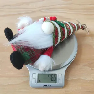 Christmas Gnome plush hanging decoration with striped knit hat on a weighing scale