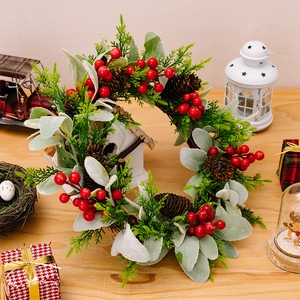 Nahaufnahme eines Weihnachtskranzes mit roten Beeren und Zapfen auf Holzhintergrund