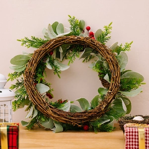 Rustikaler Weihnachtskranz mit roten Beeren, grünen Blättern und Zapfen auf Holztisch