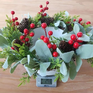 Nahaufnahme eines Weihnachtskranzes mit roten Beeren auf einer Waage, Gewicht 271g