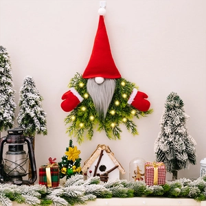 Close-up of glowing LED Christmas gnome wreath with red hat and green pine needles