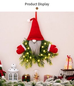 Detail of lit Christmas gnome wreath with artificial greenery and warm LED lights