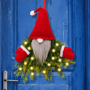 Detail of a lighted Christmas gnome wreath with LED lights on a dark blue wooden door
