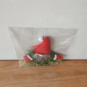 Close-up of a lit Christmas gnome wreath with red hat and green pine needles in packaging