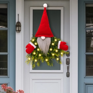 Lighted Christmas gnome wreath with green pine needles and warm LED lights on a white door
