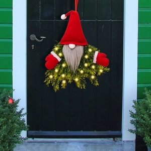 Lighted Christmas gnome wreath with green pine branches and LED lights on a dark door