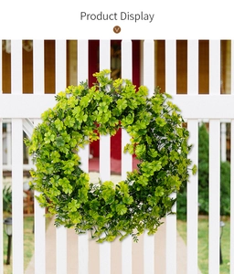 Close-up of lush green clover wreath hanging on a white wooden fence for home decoration