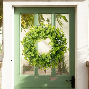 Detail of St. Patrick's Day shamrock wreath hanging on a green wooden door