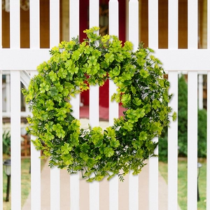 Lush St. Patrick’s Day green shamrock wreath hanging on a white garden fence