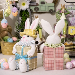 Detail of plush Easter bunnies on gift box bases with festive garden decor background