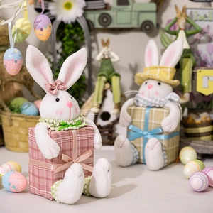 Detail of plush Easter bunny figurines sitting on festive gift boxes with colorful eggs