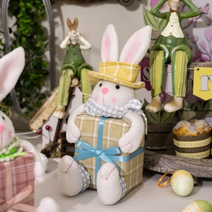Detail of plush Easter bunny with yellow plaid hat and blue scarf holding a gift box