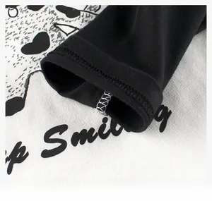 Detail of knitted cotton hem with Keep Smiling print and black heart pattern