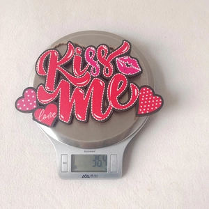 Close-up of red Kiss Me wooden heart sign for Valentine décor with hanging rope