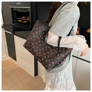 Detail of printed PU tote bag with cherry pattern and reinforced black leather straps