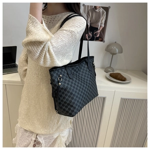 Detailed view of black tote bag with M-letter print worn with a white knit top