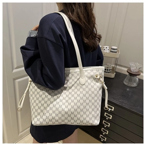 Detail of white tote bag featuring black M letter prints and slim shoulder straps