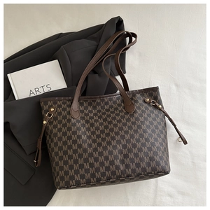 Detail of brown tote bag featuring M-letter print pattern and metallic drawstring hardware