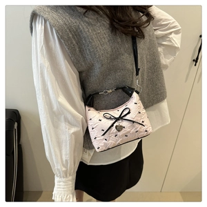 Detail of pink floral jacquard bag with black bow and heart pendant crossbody