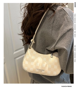 Detail der beige karierten Hobo-Tasche mit schmalem Gurt und Logo auf der Schulter