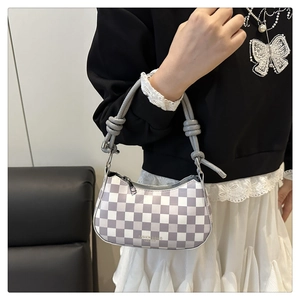 Detail der karierten Hobo-Tasche mit Knotenseilgriff und Metallringen im Fokus