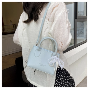 Detail of light blue lychee pattern bucket bag with pearl lace charm on a model