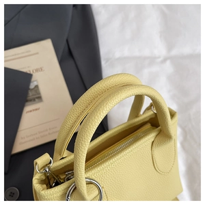 Close-up of light yellow litchi grain leather bucket bag with silver metal hardware