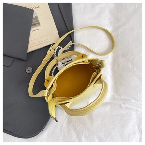 Top view of yellow textured leather handbag with lace pearl pendant and zipper closure
