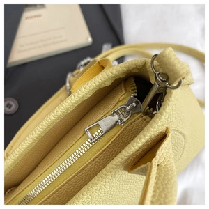 Close-up of yellow litchi pattern leather bag with silver metal zipper and swivel hook