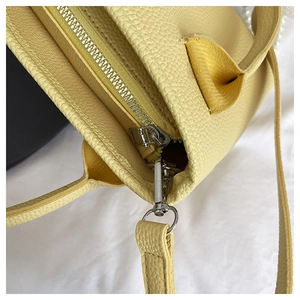 Detail of yellow pebbled leather bucket bag showing zipper closure and silver hardware