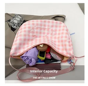 Internal capacity of pink plaid shoulder bag showing umbrella, phone, and makeup