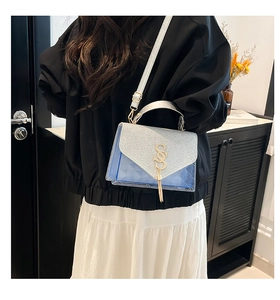 Detail of blue quilted shoulder bag with silver sequin flap and metallic S logo charm