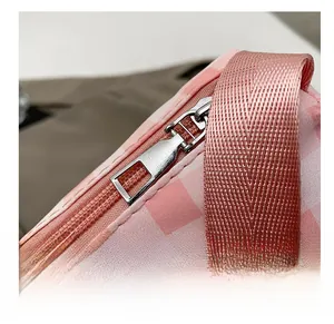 Detail shot of smooth silver metal zipper on pink checkered pattern crossbody bag