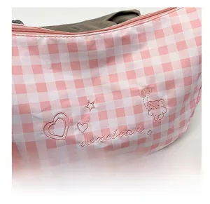 Close-up of pink checkered shoulder bag featuring detailed heart and bear embroidery